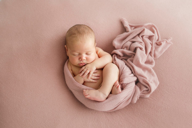 Newborn baby on blush pink blanket