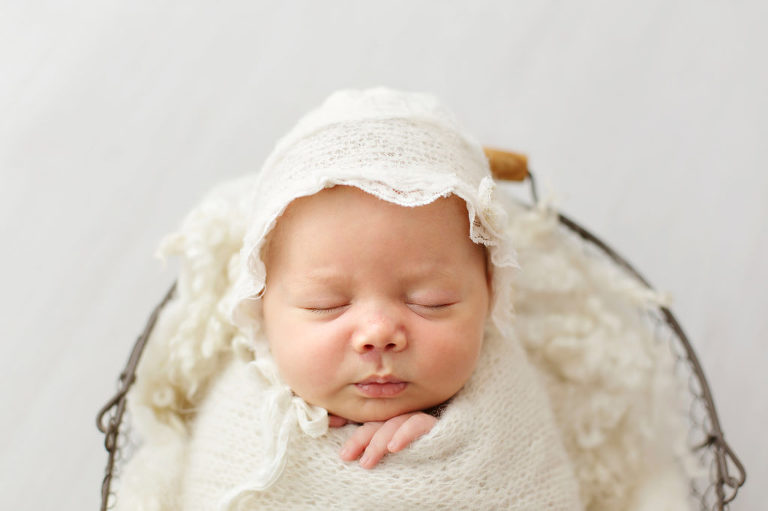 close up of baby girl in white basket