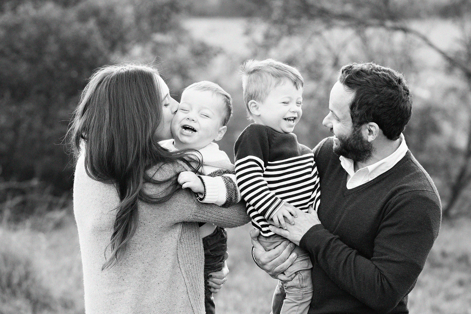 mum and day holding twin boys and laughing together