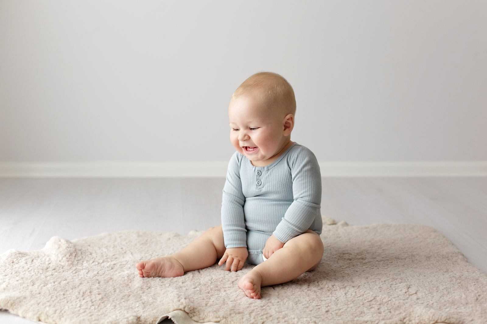 Baby in a blue romper laughing
