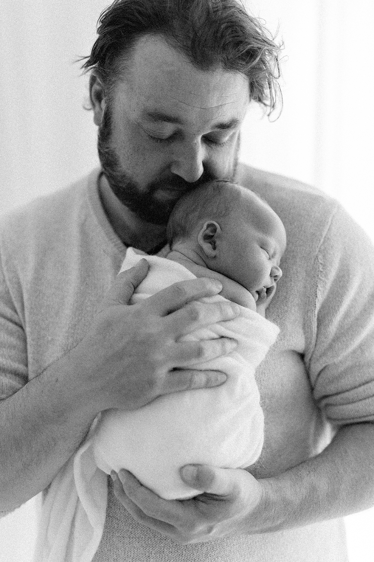 black and white image of a newborn baby being held by dad
